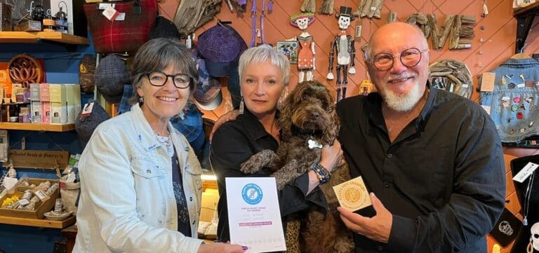 two women, one man, and their dog line up for a photo inside their trinket shop