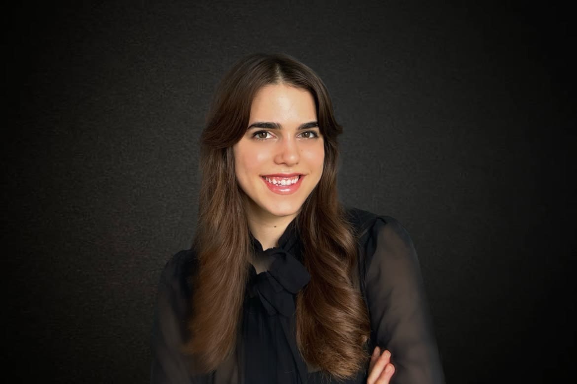 Young lady dressed in black stands in front of black background for professional headshot